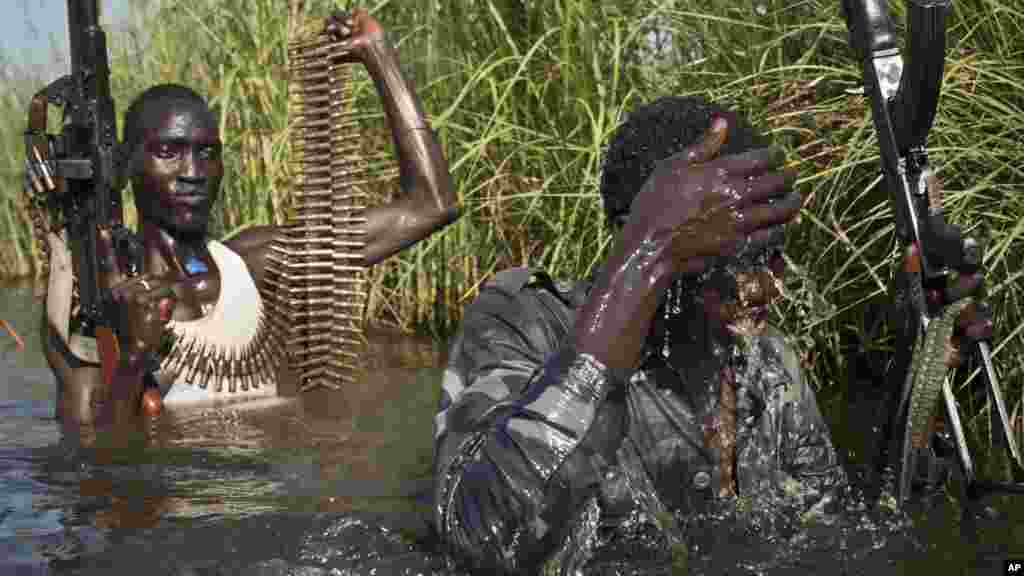Des rebelles en patrouille encadrent des civiles de l’ethnie Nuer qui traversent les eaux dans un camp près de la base de l’ONU à Bentiu, 27 octobre 2015. . (AP Photo/Matthew Abbott)