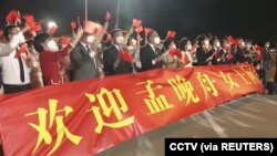 在广东深圳宝安国际机场打着横幅欢迎孟晚舟回国的人群。（2021年9月25日）