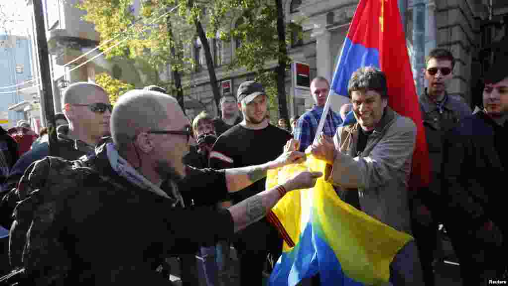 Supporters of the self-proclaimed republics of Donbass and Luhansk tear an Ukrainian national flag before an anti-war rally in Moscow, Sept. 21, 2014.
