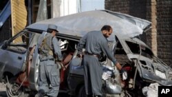 Dua polisi Afghanistan memeriksa lokasi ledakan bom mobil (foto: dok). Seorang pria berseragam polisi Afghanistan menembak tewas tiga tentara Inggris, Minggu (1/7). 
