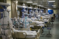 FILE - Medical workers in protective suits attend to novel coronavirus patients at the intensive care unit (ICU) of a designated hospital in Wuhan, Hubei province, China, Feb. 6, 2020.