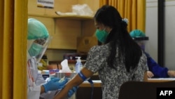 Seorang relawan sedang menjalani pemeriksaan sebelum menerima suntikan calon vaksin Covid-19 dalam uji klinis di Rumah Sakit Universitas Padjajaran, di Bandung, Jawa Barat, 6 Agustus 2020. (Foto: Timur Angin/AFP)
