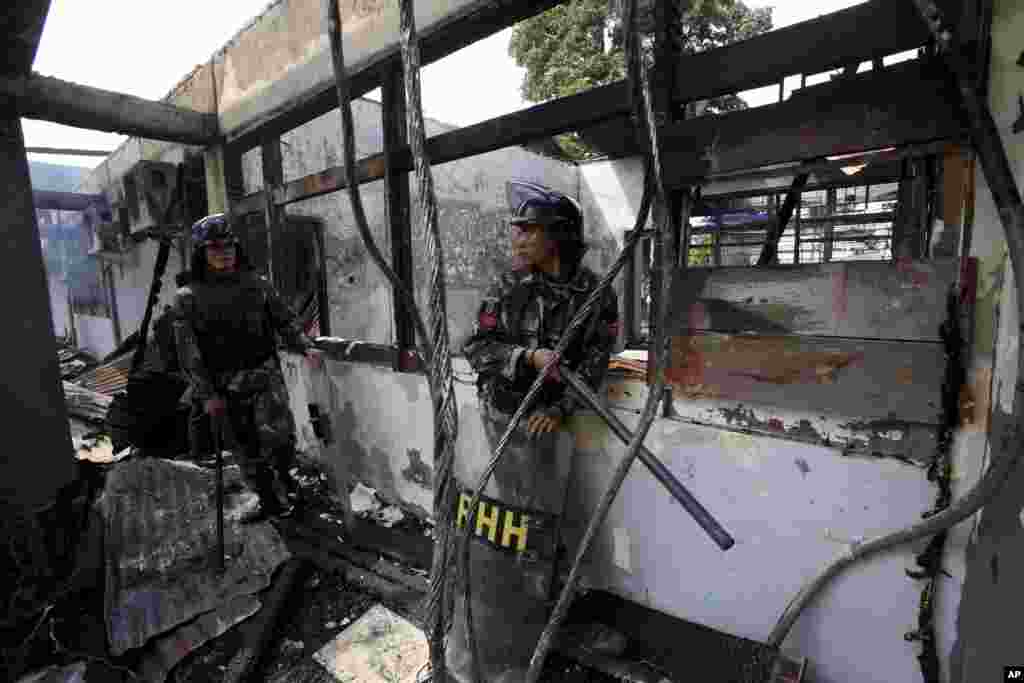 Indonesian soldiers stand guard in a burned down room at Tanjung Gusta prison following a riot in Medan, North Sumatra, Indonesia, July 12, 2013. 