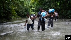 FILE - Haitian migrants wade through a river as they cross the Darien Gap, from Colombia into Panama, hoping to reach the U.S., Oct. 15, 2022. 