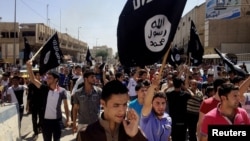 FILE - Demonstrators chant pro-Islamic State group slogans as they wave the group's flags in front of the provincial government headquarters in Mosul, Iraq, June 16, 2014.