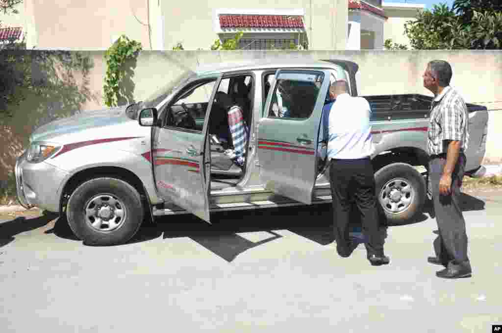 Tunisian police officers inspect Mohamed Brahmi's vehicle in which he was shot to death, outside his home in Tunis, July 25, 2013. 