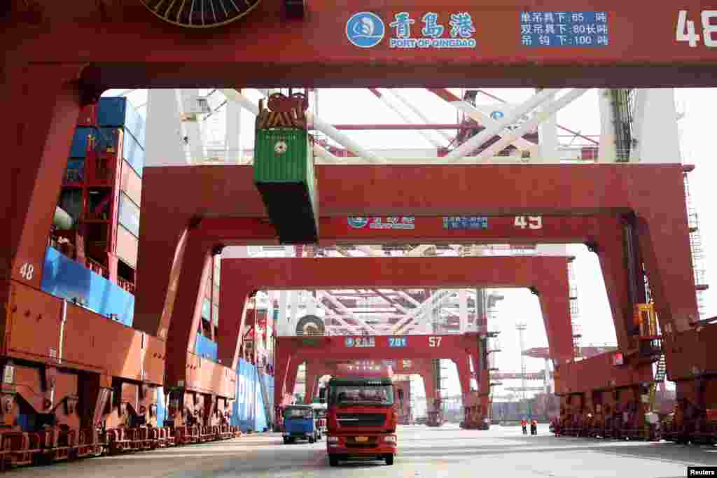 2018年4月8日，在中国山东青岛的一个港口，龙门吊车列队，卡车运输集装箱。