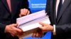 EU chief Brexit negotiator Michel Barnier, left, and European Council President Donald Tusk flip through the pages of a draft withdrawal agreement at the Europa building in Brussels, Nov. 15, 2018.