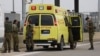 FILE - Israeli soldiers stand next to a military ambulance on a road near the West Bank Jewish settlement of Elkana, Nov. 15, 2022. A Palestinian killed two Israelis and wounded four others in an attack in a settlement before he was shot and killed by Israeli security personnel.