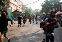 Hombres corren durante una protesta contra el golpe militar, en Rangún, Myanmar, el 28 de marzo de 2021.