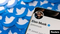 FILE PHOTO: Illustration shows Elon Musk's Twitter profile on smartphone and printed Twitter logos