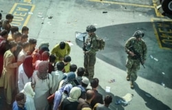 Dua tentara AS melakukan pengamanan sementara warga Afghanistan yang berusaha meninggalkan negaranya memenuhi bandara internasional Hamid Karzai di Kabul (16/8).