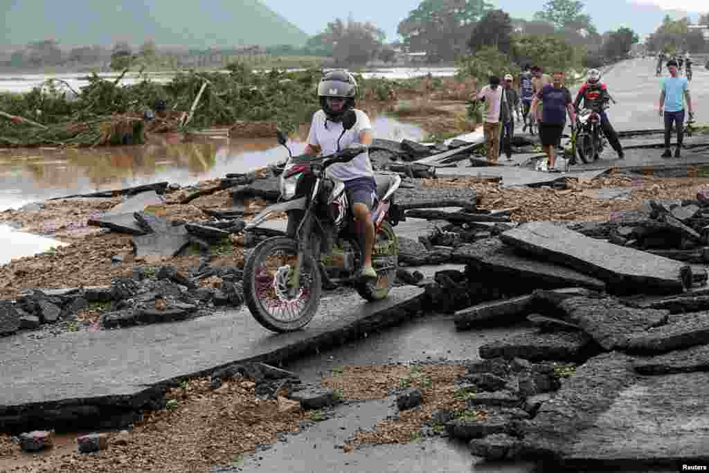 Un hombre conduce su motocicleta en un puente dañado tras el paso de la tormenta Eta, en Pimienta, Honduras, el 6 de noviembre de 2020.