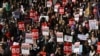 Manifestantes seguram cartazes enquanto se reúnem em Trafalgar Square apelando ao fim da violência masculina contra as mulheres, em Londres, a 8 de março de 2025, para assinalar o Dia Internacional das Mulheres.