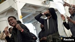 Para migran bernyanyi di atas kapal Aquarius yang sedang dalam perjalanan menuju Spanyol, 16 Juni 2018. Aquarius adalah kapal pencarian dan penyelamatan (SAR) yang dikelola lembaga swadaya masyarakat, SOS Mediterranee dan Dokter Tanpa Tapal Batas.