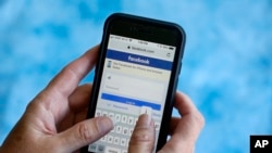 In this Aug. 21, 2018, file photo, a Facebook start page is shown on a smartphone in Surfside, Fla. Facebook says it's working to help limit the spread of misinformation and harmful content about the coronavirus and will focus on providing helpful inform