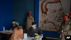 Miembros del Consejo Electoral de Venezuela, con mascarillas y visores de protección, certifican la autenticidad de los datos de votantes en Caracas, Venezuela. el 25 de julio de 2020.