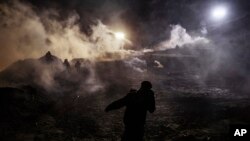 Migrantes corren del gas lacrimógeno lanzado por agentes de Protección Fronteriza de EE.UU. hacia el lado mexicano de la valla en la frontera, después que escalaron la valla tratando de cruzar a San Diego, California desde Tijuana, México, el martes 1 de enero de 2019.