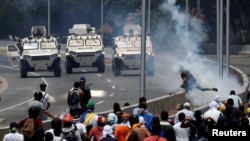 Opposition demonstrators face military vehicles near the Generalisimo Francisco de Miranda Airbase "La Carlota" in Caracas, Venezuela April 30, 2019. (REUTERS/Carlos Garcia Rawlins)