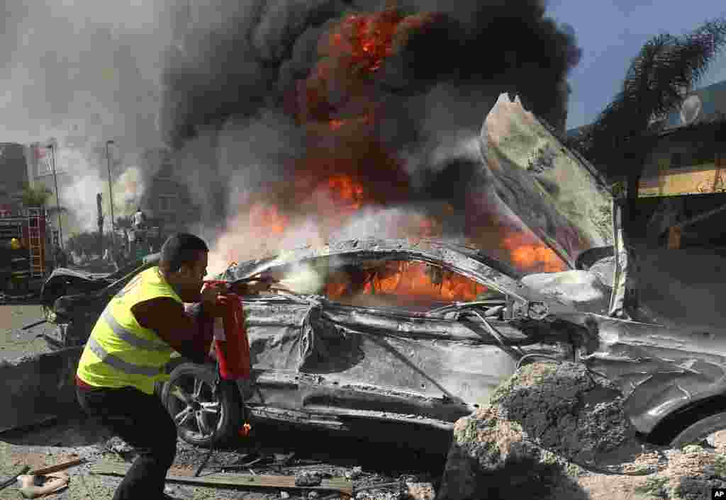 A Lebanese firefighter extinguishes a burned car at the site of an explosion, near the Kuwaiti Embassy and Iran's cultural center, in the suburb of Beir Hassan, Beirut, Lebanon, Feb. 19, 2014.