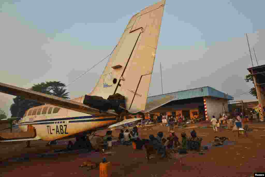 Sebuah keluarga duduk dekat pesawat di kamp pengungsi di bandar udara internasional M'Poko di Bangui (20/2). (Reuters/Luc Gnago)