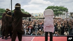 Polisi syariah melakukan hukuman cambuk terhadap seorang pria gay di luar masjid di Banda Aceh, provinsi Aceh, hari Selasa (23/5). 