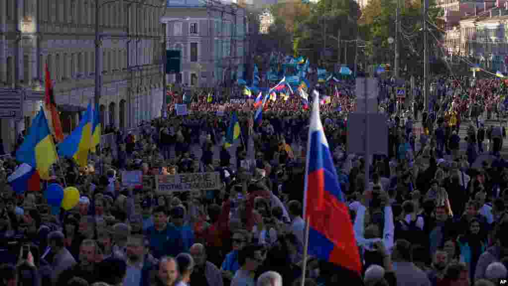 People carry Russian and Ukrainian flags during an anti-war rally in downtown Moscow, Russia, Sept. 21, 2014.