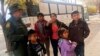 FILE - A migrant family from Central America waits outside the Annunciation House shelter in El Paso, Texas, after a U.S. Immigration and Customs Enforcement officer drops them off, Nov. 29, 2018. 