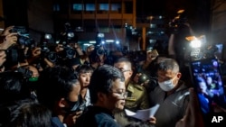 Aktivis pro-demokrasi dan pengacara hak asasi manusia Arnon Nampha, tengah, di kantor polisi setelah unjuk rasa di Monumen Demokrasi di Bangkok, Thailand. (Foto: AP)
