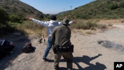 Un agente de la Patrulla Fronteriza de EEUU registra a un inmigrante que desea obtener asilo antes de que el hombre sea trasladado y procesado, el 5 de junio de 2024, cerca de Dulzura, California. 