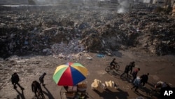 Palestinos pasan junto a montones de basura ardiendo en la Ciudad de Gaza, que no cuenta con sistema de recogida de basuras, el 12 de febrero de 2025.