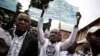 Des Congolais brandissent des pancartes lors d'une manifestation après un service catholique pour commémorer les victimes de la répression de la marche du mois dernier à l'extérieur d'une cathédrale à Kinshasa, le 12 janvier 2018.