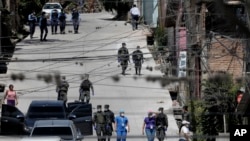 Trabajadores del Ministerio de Salud están acompañados por soldados y policías mientras investigan en el vecindario acordonado de Lincoln, luego de que varias personas dieran positivo por el nuevo coronavirus, en Tegucigalpa, Honduras.