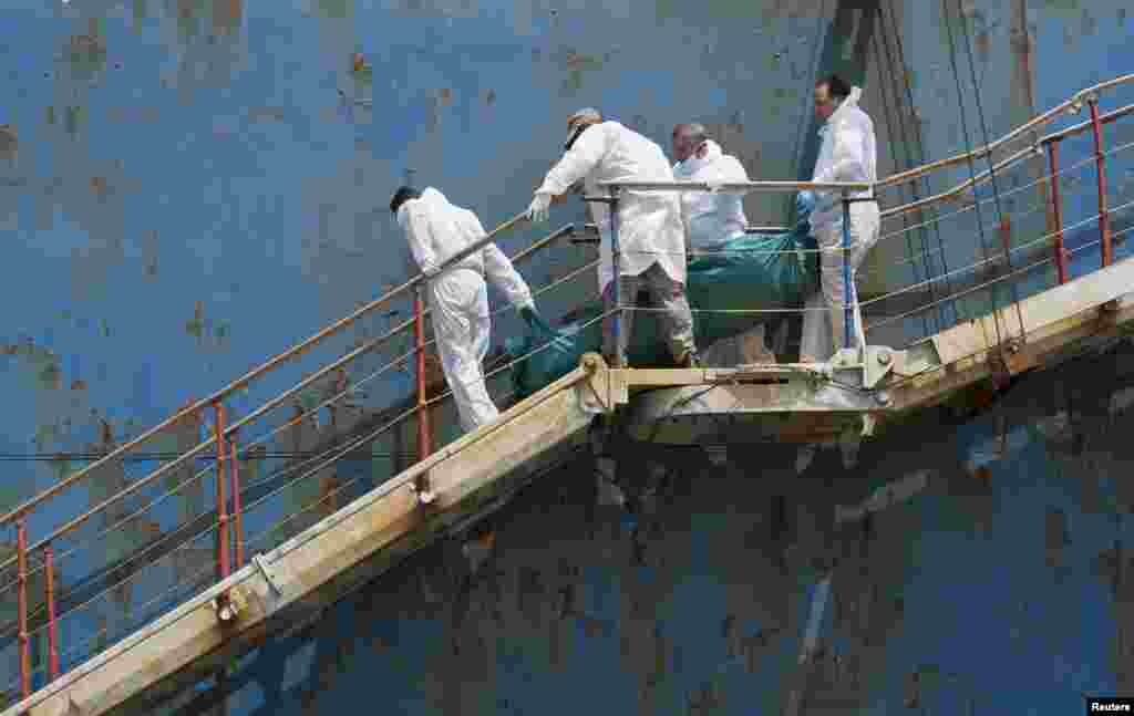 People carry the body of a dead migrant from a merchant ship as they arrive in the Sicilian harbor of Catania, southern Italy, May 5, 2015. 