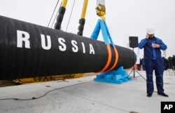 Seorang pekerja konstruksi Rusia berbicara di telepon seluler di Teluk Portovaya sekitar 170 km barat laut dari St. Petersburg, Rusia. (Foto: AP)