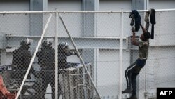 ARCHIVES - Un jeune tente d'escalader la clôture frontalière dans l'exclave espagnole de Ceuta, à la frontière avec le Maroc, le 13 avril 2021. 