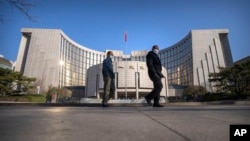 ARCHIVO - Peatones con mascarilla pasan ante el Banco Popular de China en Beijing, el 3 de marzo de 2023. La institución indicó este miércoles 24 de enero que reduciría la proporción de reservas exigida a los bancos para ayudar a reactivar la economía.