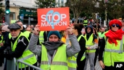 Une manifestante portant son gilet jaune tient une pancarte lors de la visite du ministre français des Affaires étrangères Jean-Yves Le Drian à Biarritz, dans le sud-ouest de la France, le 18 décembre 2018.