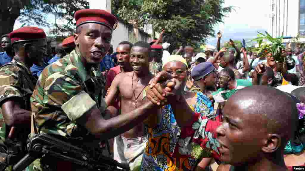 La foule salue des soldats alors qu'elle célèbre après l’annonce de la destitution du président Pierre Nkurunziza par un haut gradé de l’armée à Bujumbura, au Burundi le 13 mai 2015.