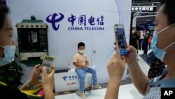 Arhiva - Posetioci prave fotografije stare telefonske govornice i deteta na štandu Čajna Telekoma tokom Kineskog međunarodnog sajma trgovine i usluga (CIFTIS), u Pekingu, Kina, 5. septembra 2021.