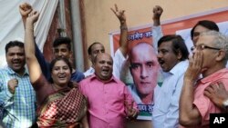 Friends of Indian naval officer Kulbhushan Jadhav celebrate the International Court of Justice order on Jadhav as they gather near a portrait of him in Mumbai, India, Thursday, May 18, 2017. The U.N. court on Thursday ordered Pakistan not to execute the Indian naval officer convicted of espionage and terrorism, in a case that has further strained relations between the Asian neighbors.