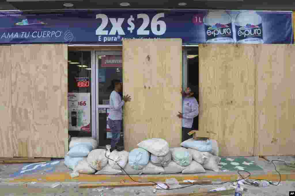 Los locales comerciales buscaron proteger sus negocios de los fuertes vientos, cubriendo sus fachadas con tablones de madera. En Cancún, se vio a pescadores asegurando sus botes en previsión del huracán.