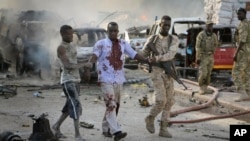 Seorang tentara Somalia menolong seorang warga sipil yang terluka dalam sebuah ledakan di Ibu Kota Mogadishu, 14 Oktober 2017. 