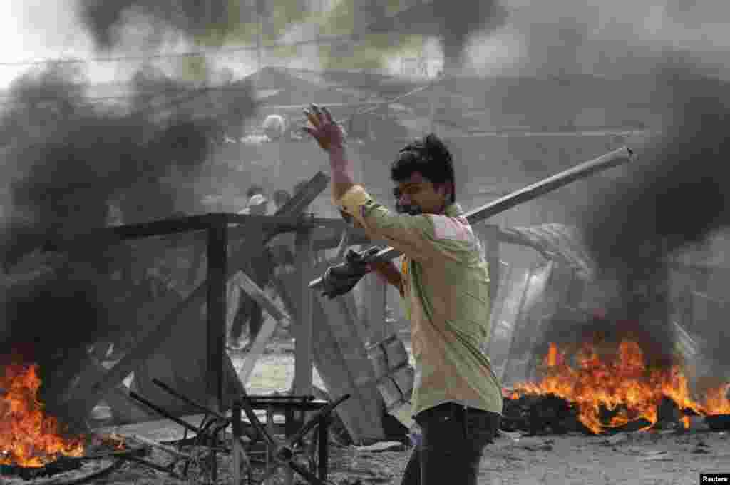 A worker carrying a metal rod reacts after clashes broke out during a protest in Phnom Penh, Jan. 3, 2014.
