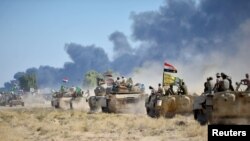 Pasukan Mobilisasi Khusus Syiah (PMF) dan tentara Irak mengendarai kendaraan lapis baja di pinggiran Hawija, Irak, 4 Oktober 2017.