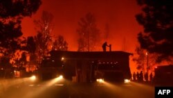 Un pompier sur le toit d’une maison en flammes dans les montagnes de Santa Cruz, en Californie, 27 septembre 2017.