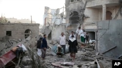 FILE - People inspect the damage of houses destroyed by Saudi-led airstrikes in Sanaa, Yemen, June. 9, 2017. 