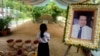 In this Nov. 20, 2016 photo, a girl stands by a portrait of Kem Ley, a Cambodian prominent political analyst, at his grave in Ang Takok, Cambodia. Kem Ley, a poor rice farmer's son turned champion of Cambodia's have-nots, was sipping his usual iced latte in the same chair he had occupied most mornings for years when a former soldier he may never have met walked into the Caltex gas station cafe. Armed with a semi-automatic Glock pistol, the assassin fired into his chest and head, execution-style. Then he walked casually away from the scene. (AP Photo/Denis Gray)