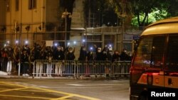FILE - Supporters of pro-democracy activists hold flashlights as a prison van carrying some of the 47 pro-democracy activists charged under the national security law arrives at Lai Chi Kok Reception Centre, in Hong Kong, March 4, 2021.