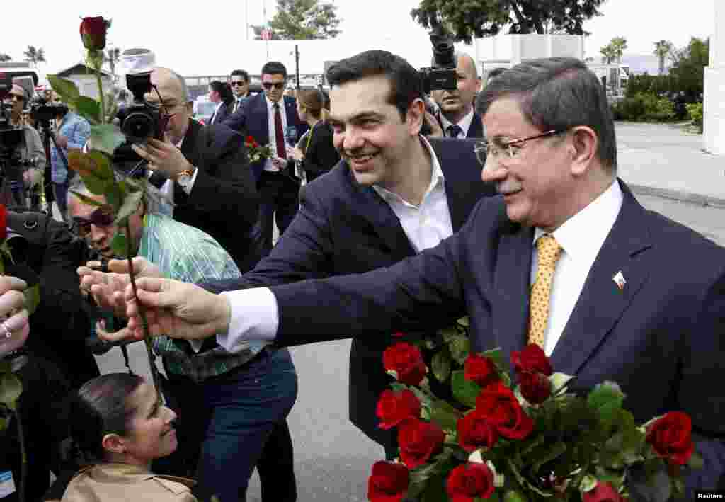 Turkish Prime Minister Ahmet Davutoglu, right, and his Greek counterpart, Alexis Tsipras, present roses to women journalists because of the International Women's Day as they meet in the Aegean port city of Izmir, western Turkey, March 8, 2016.